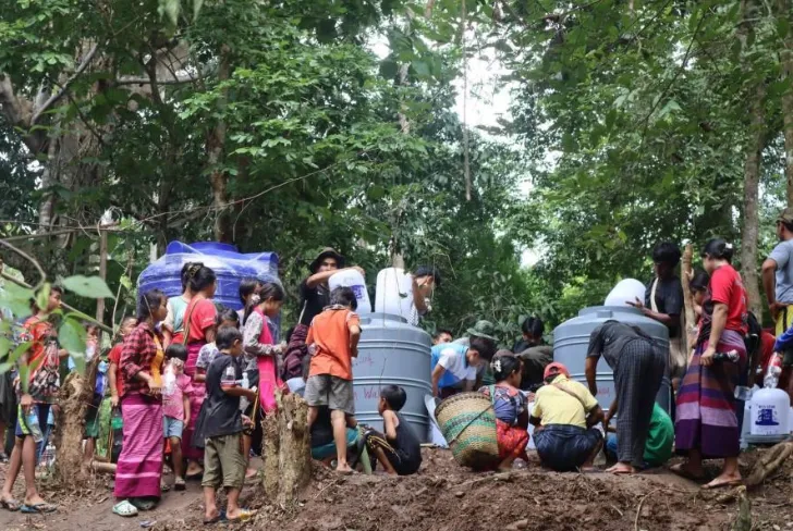 Community members gathering clean drinking water from large storage distribution tanks.