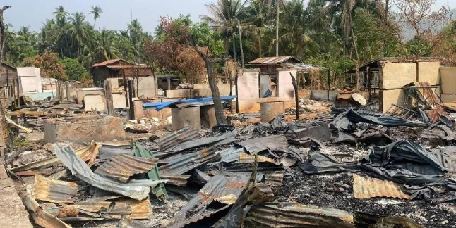 Overview of structural devastation and burnt materials in a conflict-affected village.